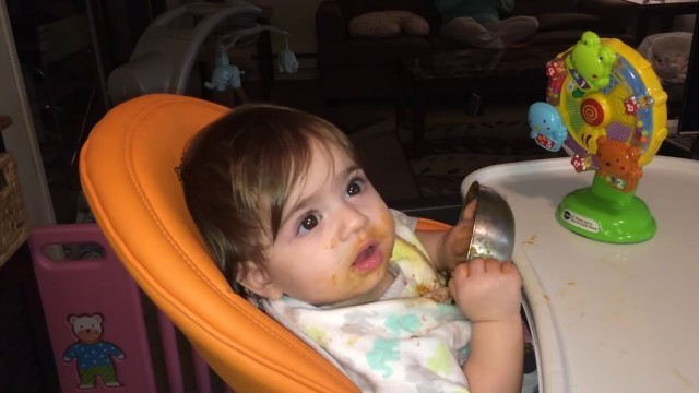 '10 months old baby girl eating food by herself'